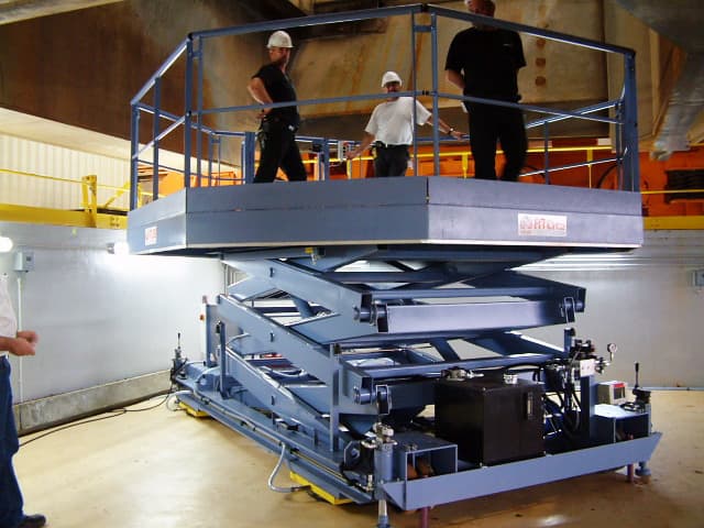 Plateforme électro-hydraulique, à triple ciseaux superposés, mobile sur sol. Elle est tractable, équipée de stabilisateurs hydrauliques et de 4 coussins d'air afin de la positionner tout azimut.