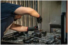 Opérateur réglant une pièce dans un étau sur la table d'un centre d'usinage, atelier Atlas Lift