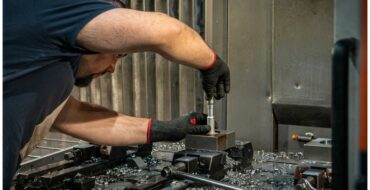 Opérateur réglant une pièce dans un étau sur la table d'un centre d'usinage, atelier Atlas Lift