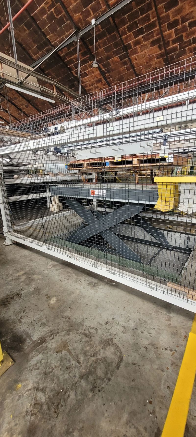 Table élévatrice Atlas Lift récente installée en fosse chez JOUBERT Plywood, derrière une protection grillagée